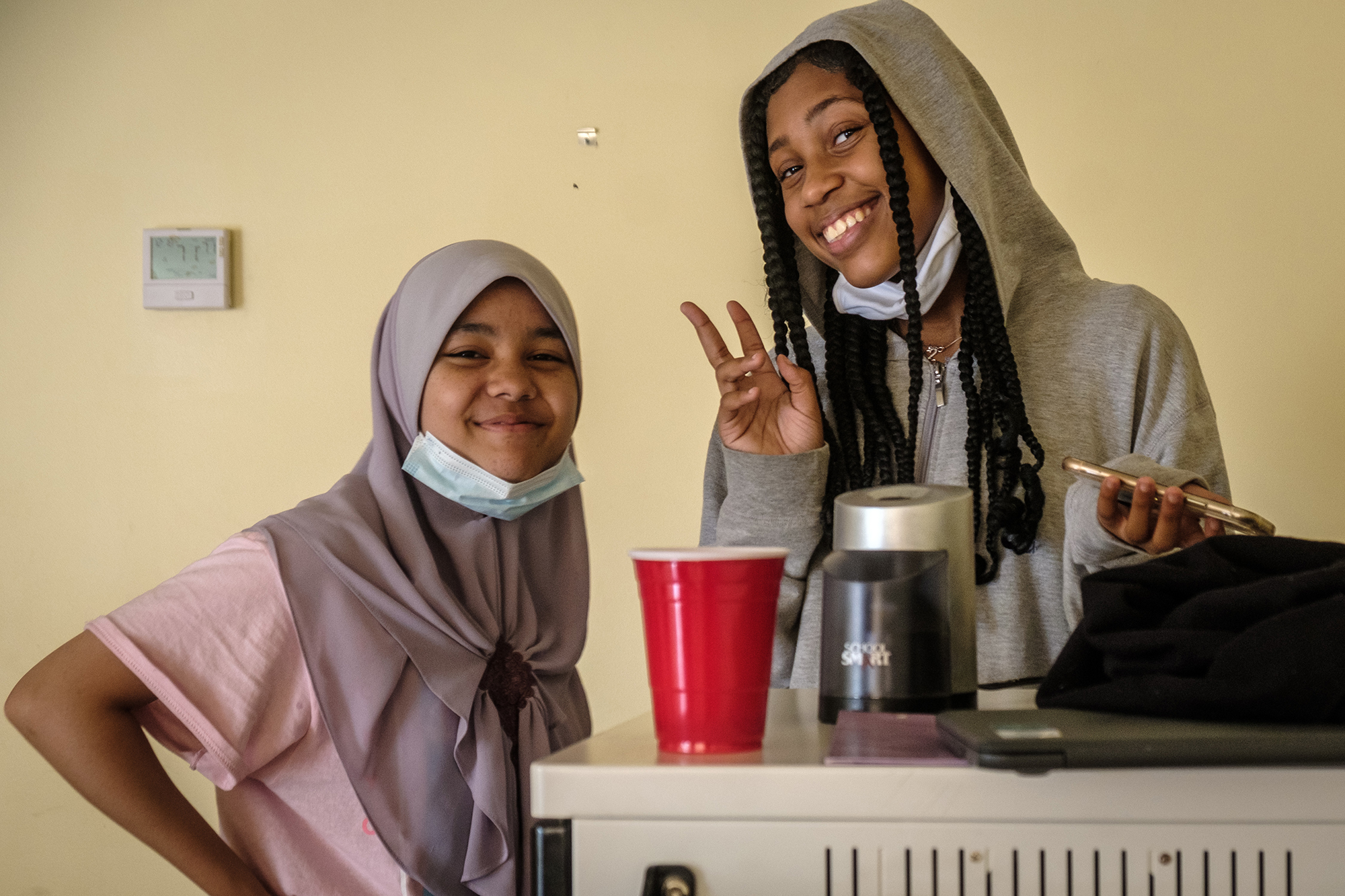 two girls smiling for a photo with one girl holding up a peace sign