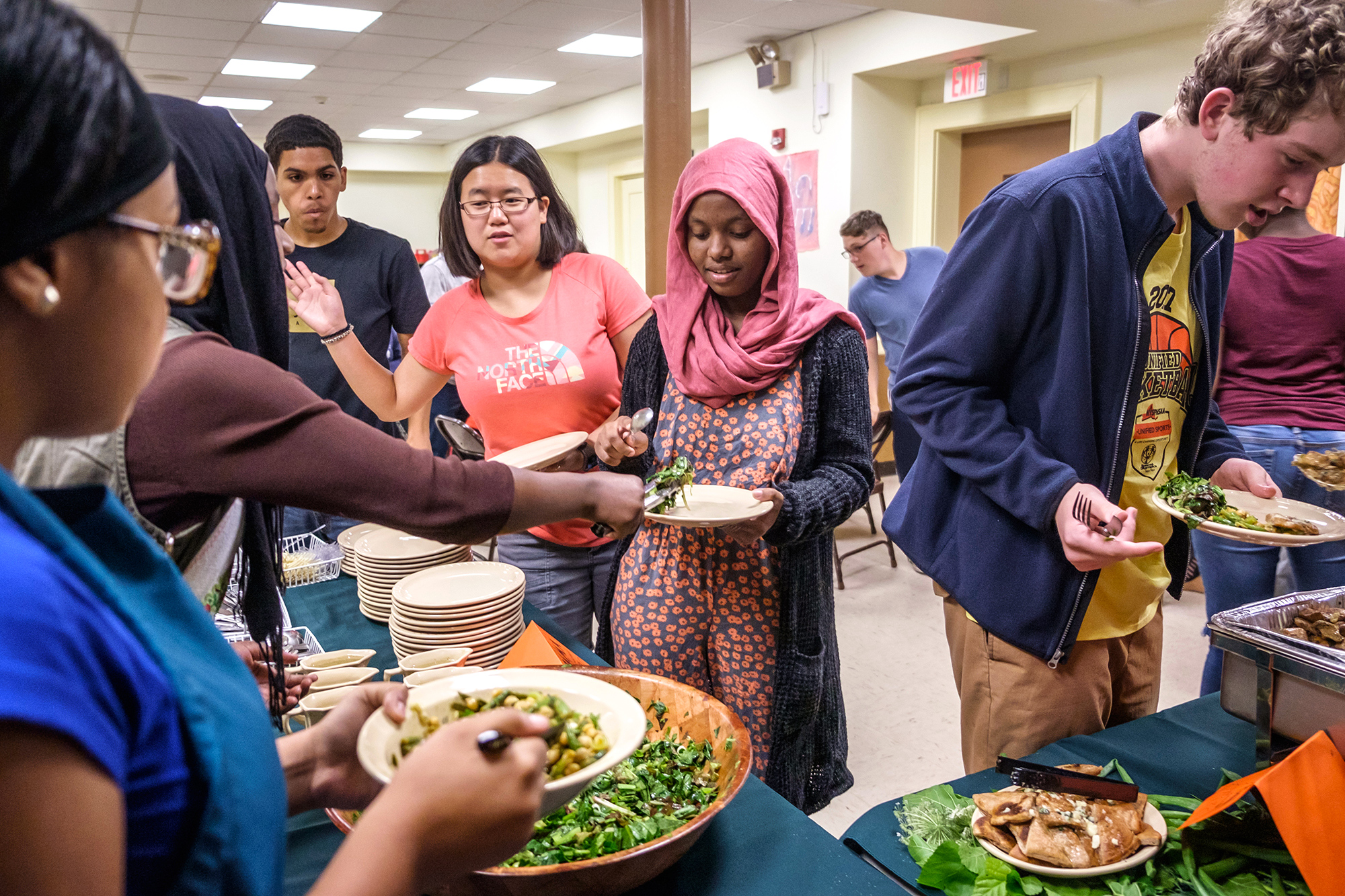 group of people getting food in a buffet line