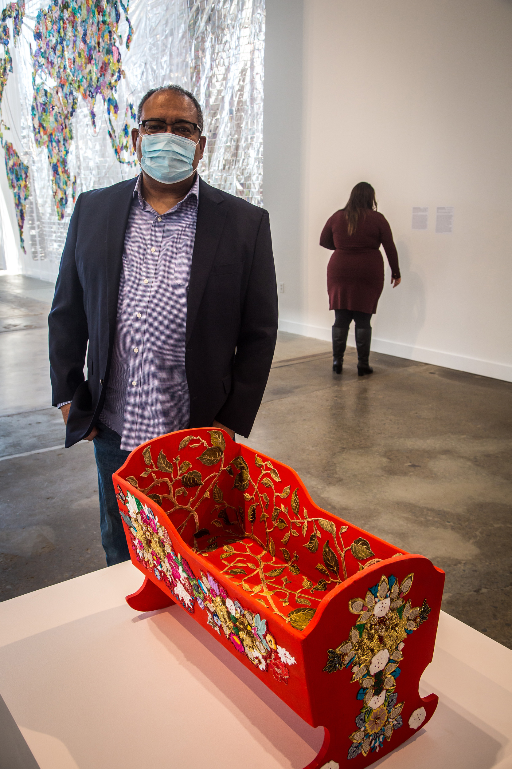 man standing behind wooden beaded cradle