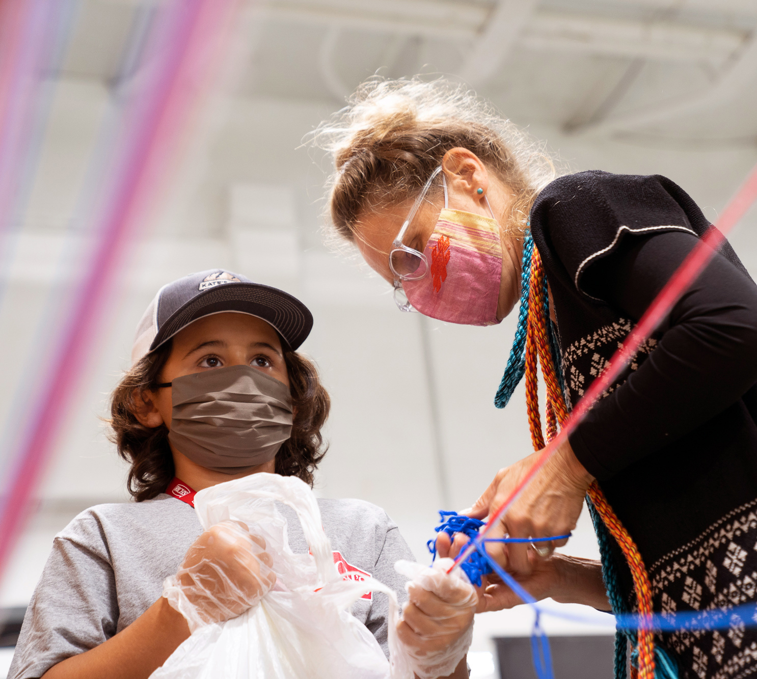 woman standing with younger boy with mask on holding string